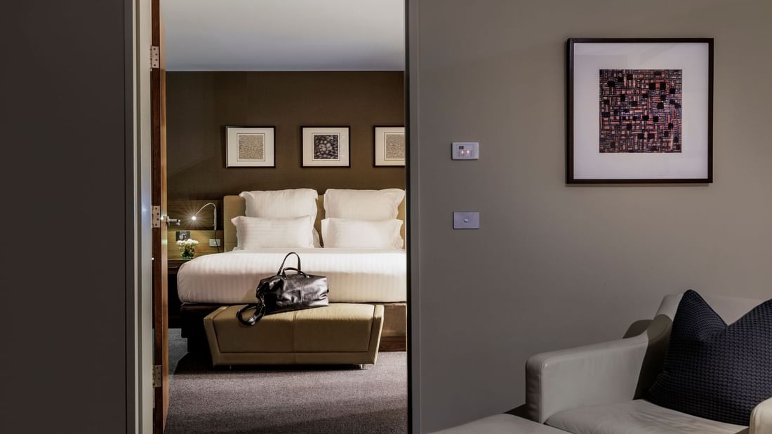 Bed with plush pillows by the ottoman and seating area in Pullman Suite Bedroom at Pullman Sydney Olympic Park