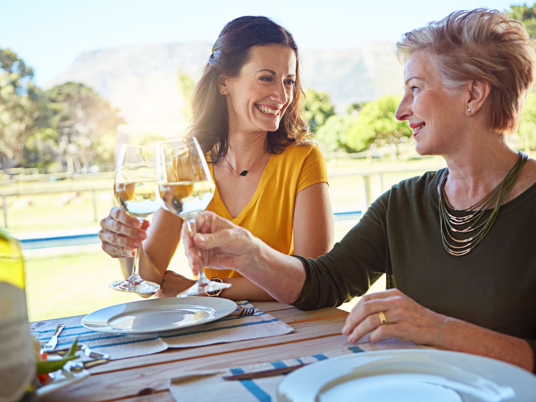 Mother and daughter drinking wine in front of vineyard