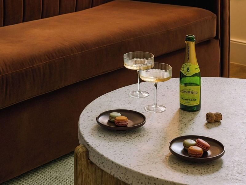 A bottle of bubbly, champagne coupes, and delicious macarons on a terrazzo table at Kenmore Village Hotel South Beach