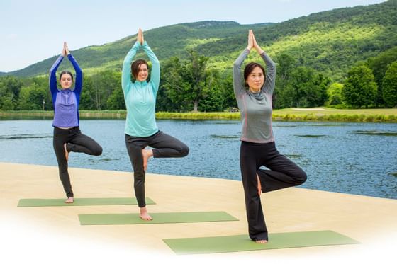 People stretching on yoga mats next to lake