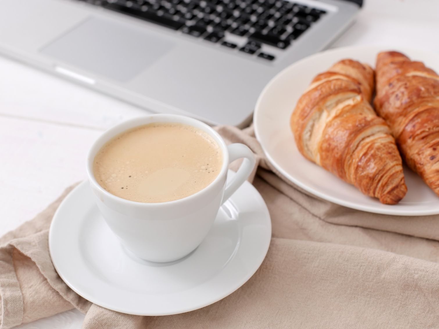 Coffee and croissants on a table with a laptop at Hotel Zero1