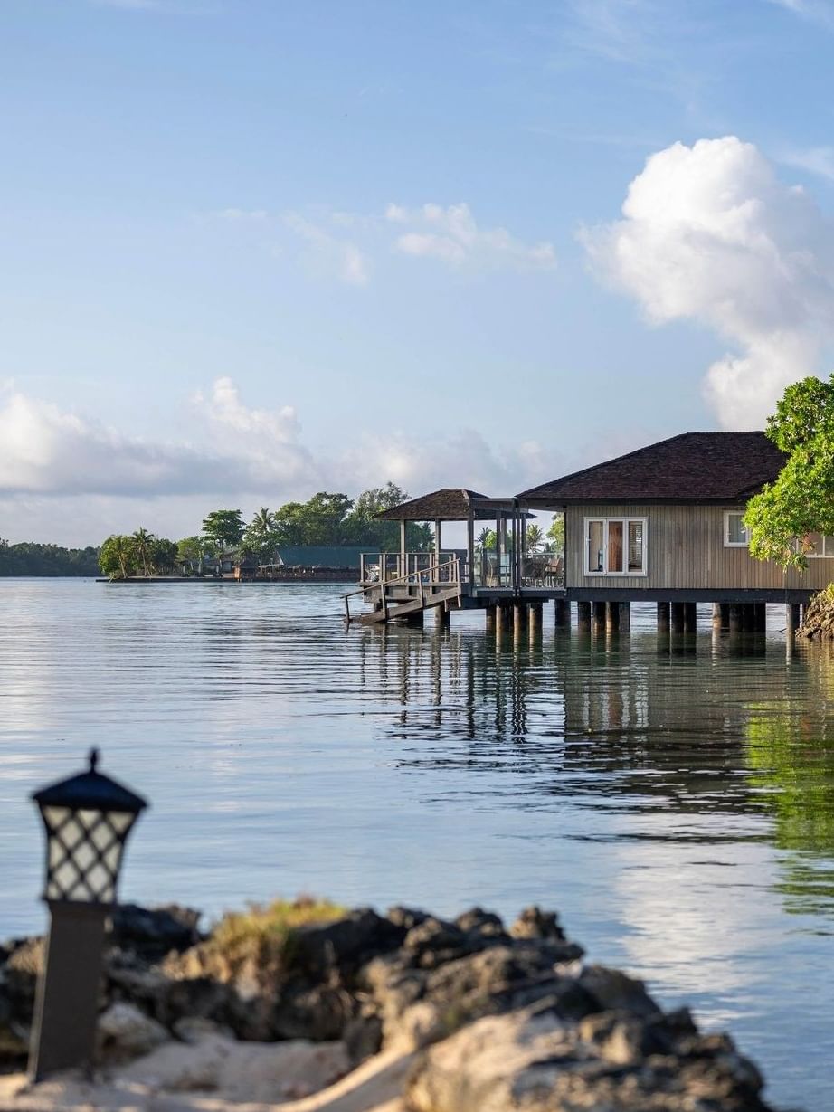 Overwater Villa reflecting on calm blue water with green trees at warwick le lagon-vanuatu