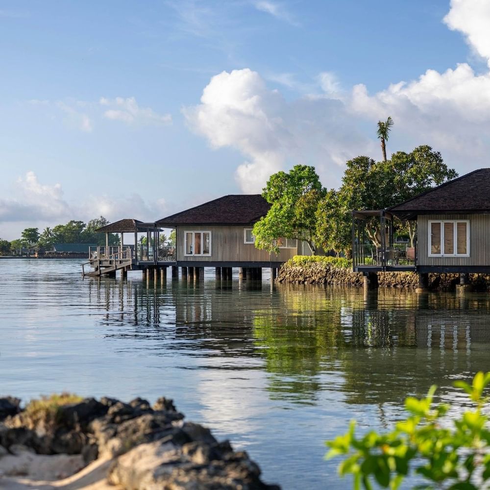 Overwater Villa reflecting on calm blue water with green trees at warwick le lagon-vanuatu