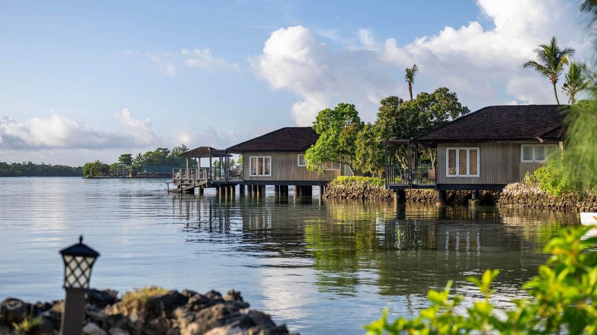 Overwater Villa reflecting on calm blue water with green trees at warwick le lagon-vanuatu