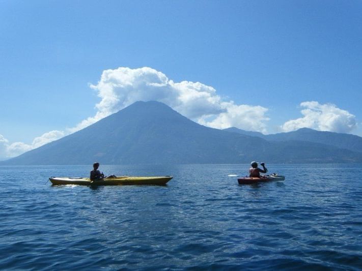 Two people kayaking on the lake with a mountain view near Porta Hotel del Lago