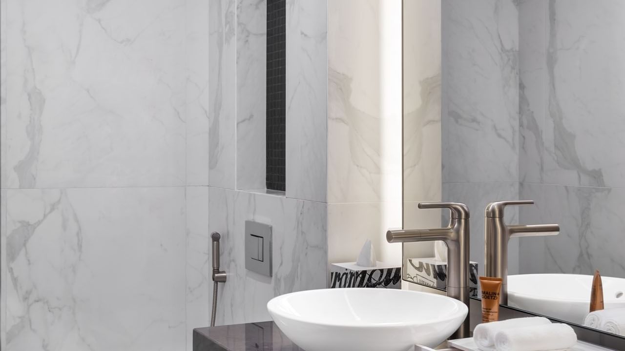 Modern bathroom sink with a brushed nickel waterfall faucet and marble countertops at Paramount Hotel Midtown