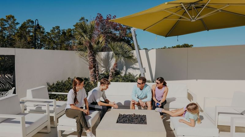Family gathered around fire pit on pool deck at The Lodge 30A