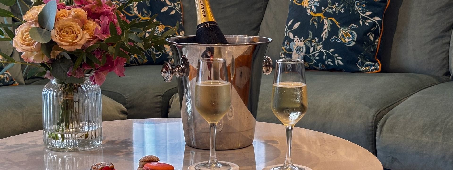 Living room scene with a vase of flowers, champagne, two filled flutes, & macarons at Warwick Reine Astrid - Lyon
