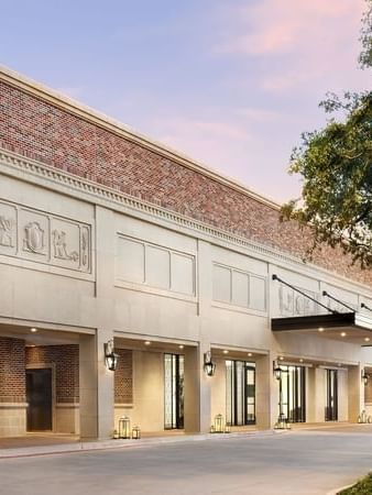 Exterior view of Warwick Melrose Dallas by lanterns under a sunset sky surrounding the grand Entrance