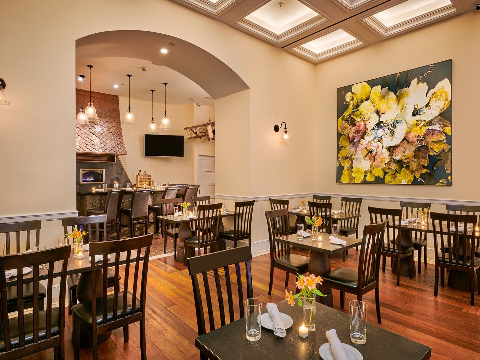 Dining area beside a floral painting near the bar at Bistango in The Kimberly Hotel, showcasing cool bars in New York City