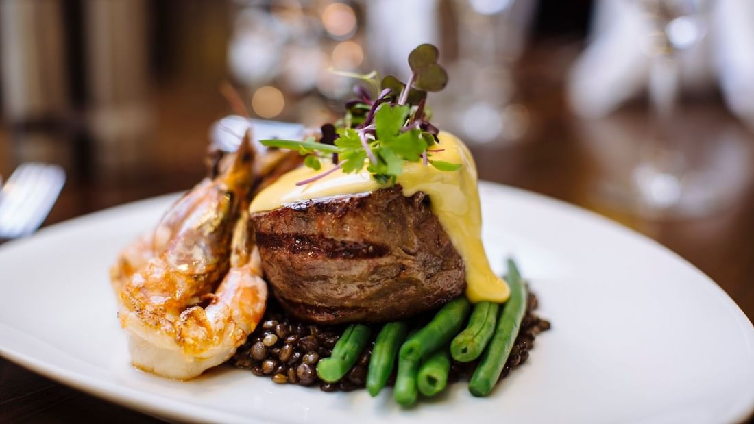 A gourmet plate featuring a grilled steak topped with hollandaise sauce, on a table at Mercure Hotel Townsville