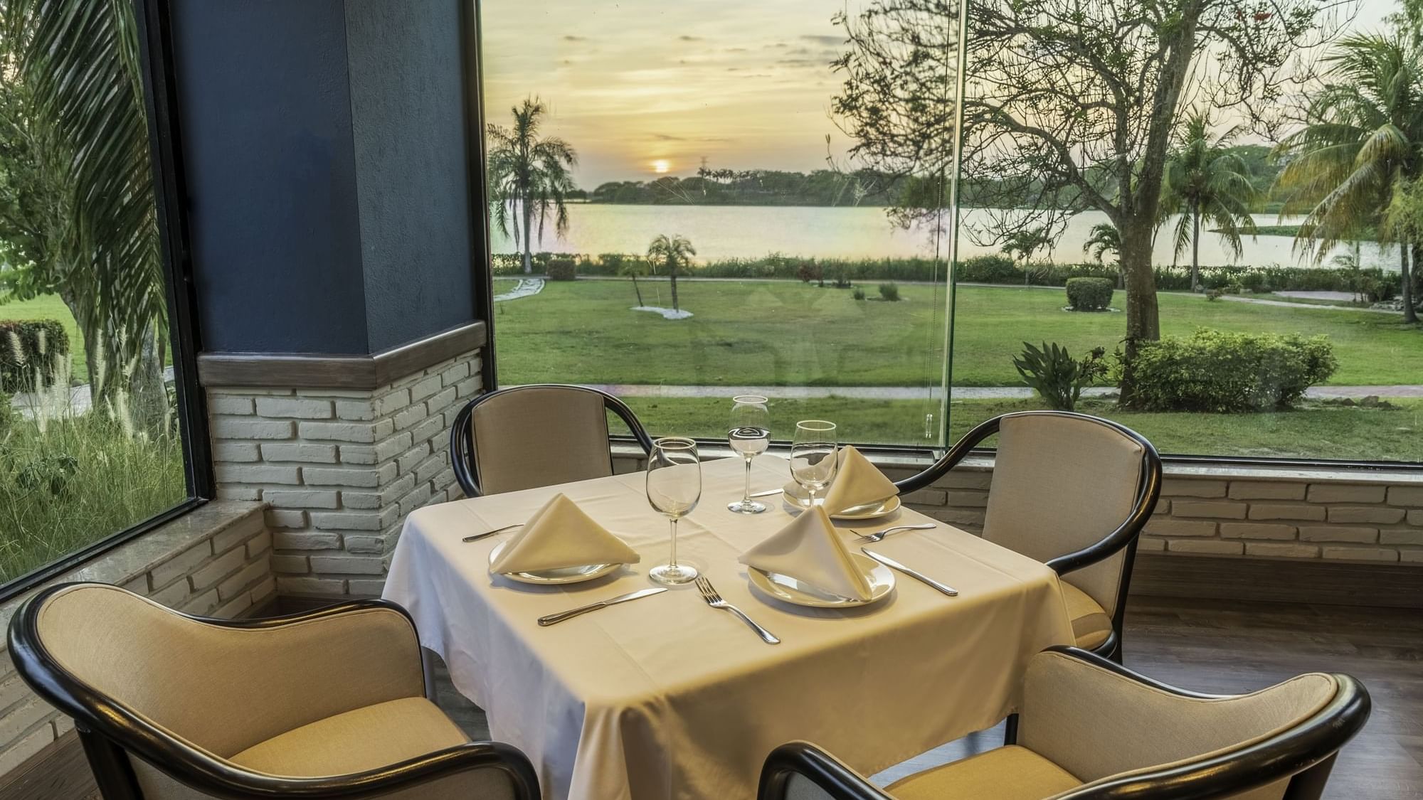 Elegant dining area with glass windows overlooking the garden at  Fiesta Inn Tampico 