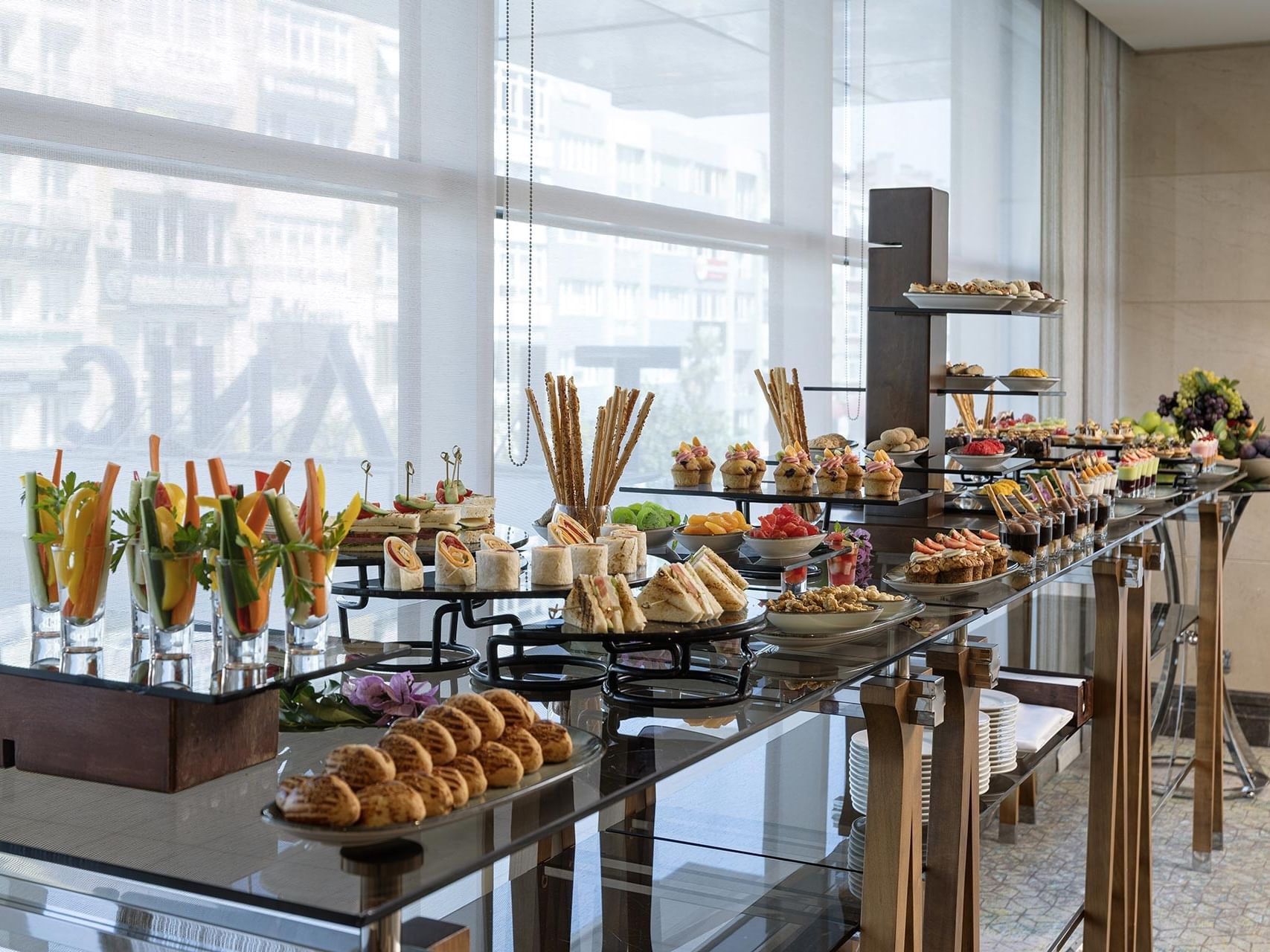 Titanic Port Bakırköy fuaye alanında geniş pencereler önünde sandviçler, meyveler ve hamur işlerini içeren zengin kahve molası büfesi.