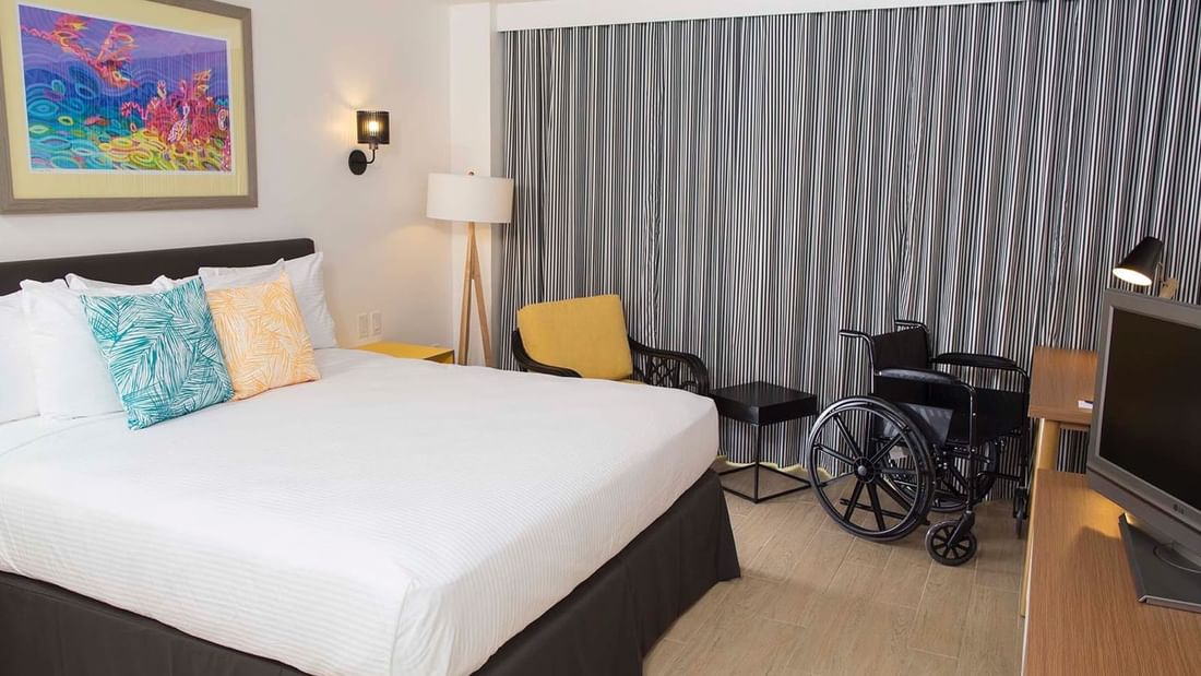 King-size bed, a TV & a wheelchair in Island View Accessible at Warwick Paradise Island Bahamas