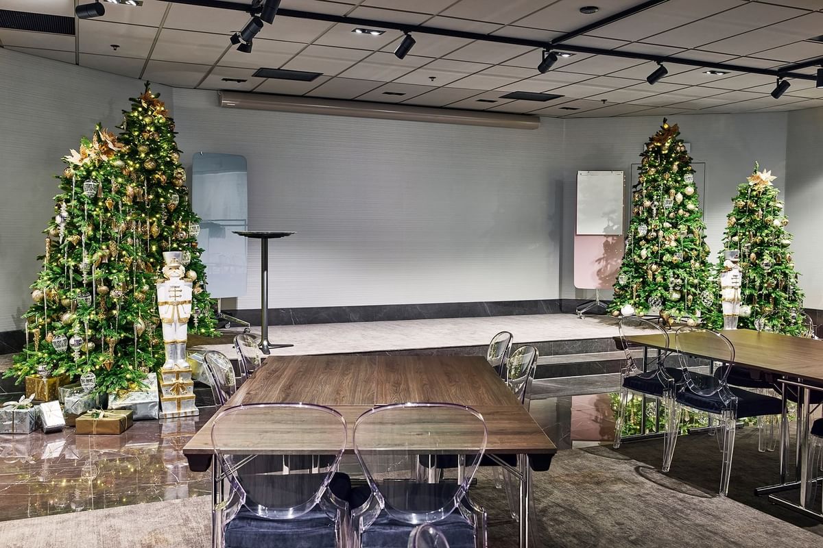 Konferensrum med julgran och bord i mitten, två bord med stolar på varsin sida.