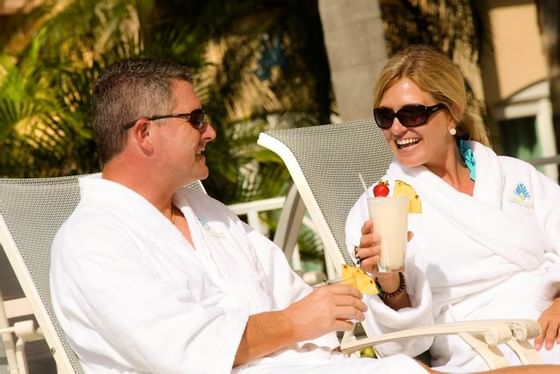 couple relaxing in robes drinking a cocktail