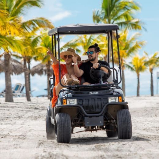 Couple driving a cart by the beach at Playa Blanca Beach Resort