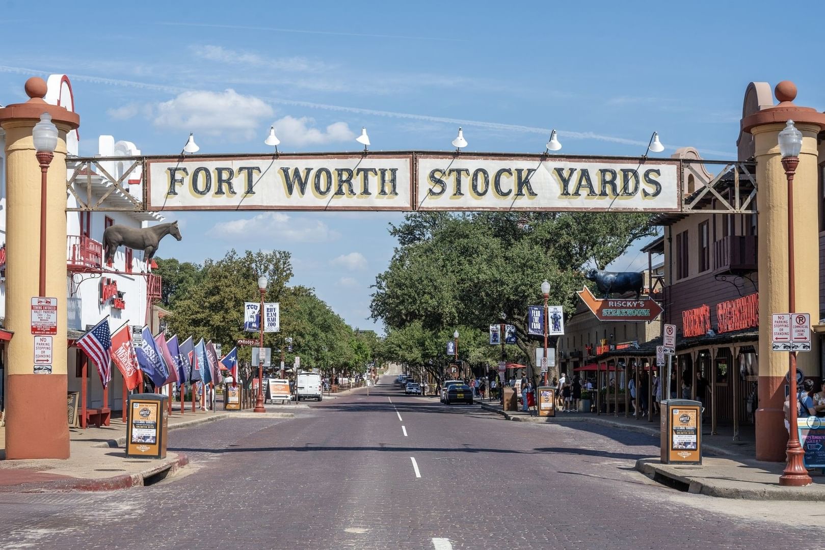 Fort Worth Stock Yards sign by flags under a blue sky surrounding a street near Warwick Melrose Dallas