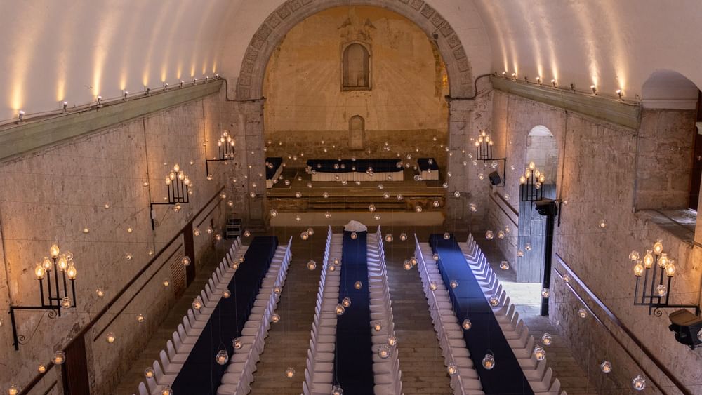Gran salón de banquetes con largas mesas azules y globos de velas colgantes en Quinta Real Oaxaca