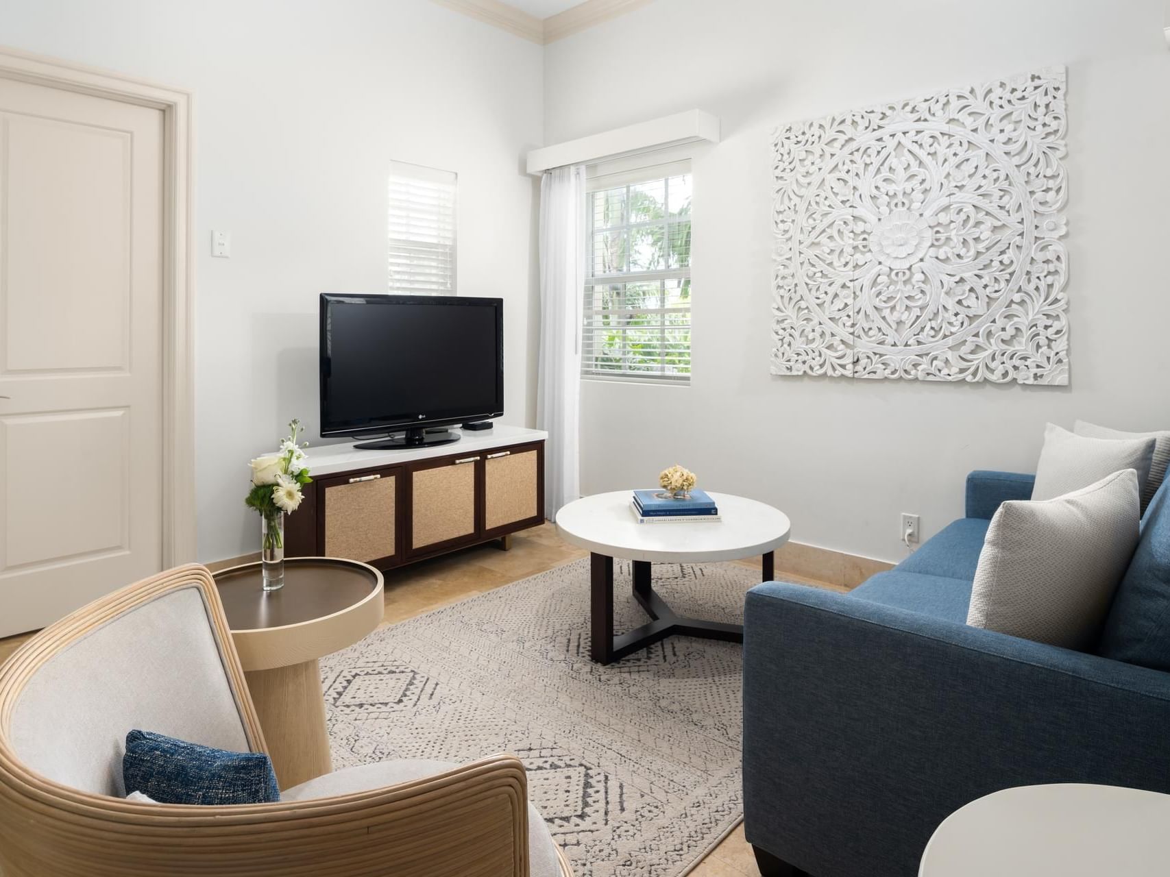 Chic 1 Bedroom Suite living room with blue sofa, TV, round table, and stylish decor at Windsong Resort On The Reef