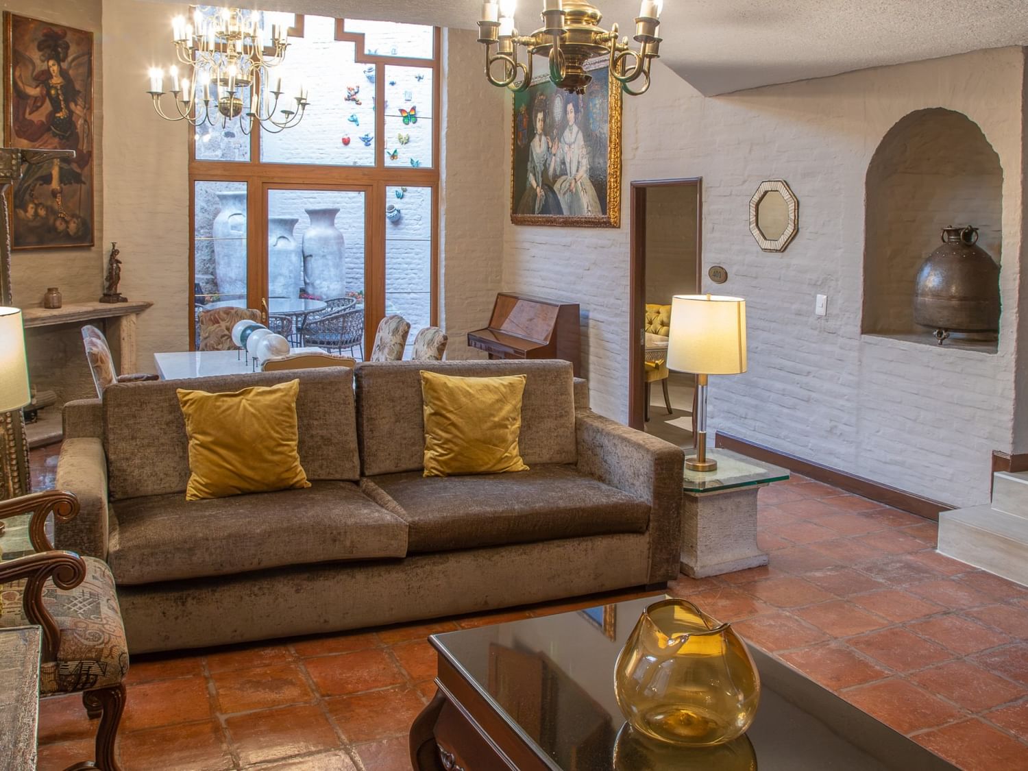 Elegante sala de estar con sofá marrón, cojines dorados y candelabros en Quinta Real Guadalajara