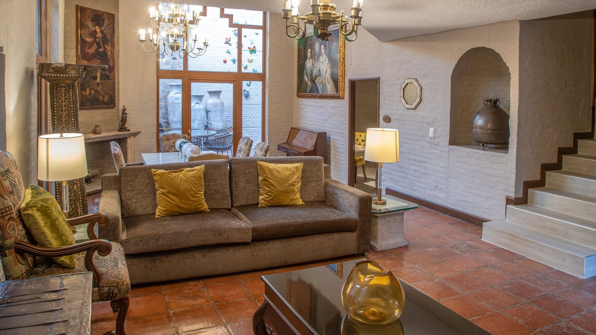 Elegante sala de estar con sofá marrón, cojines dorados y candelabros en Quinta Real Guadalajara