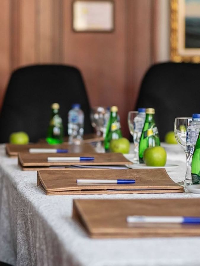 Close-up of a meeting table featuring leather folders and water bottles by black chairs in 
Al Dana at Warwick Al Jubail