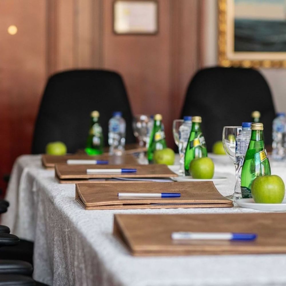 Close-up of a meeting table featuring leather folders and water bottles by black chairs in 
Al Dana at Warwick Al Jubail