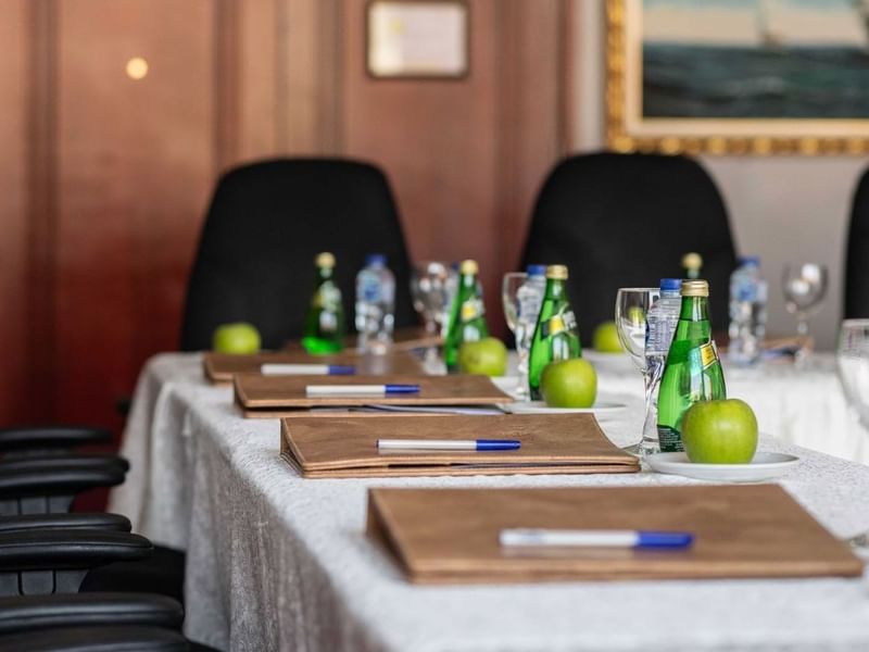 Close-up of a meeting table featuring leather folders and water bottles by black chairs in 
Al Dana at Warwick Al Jubail