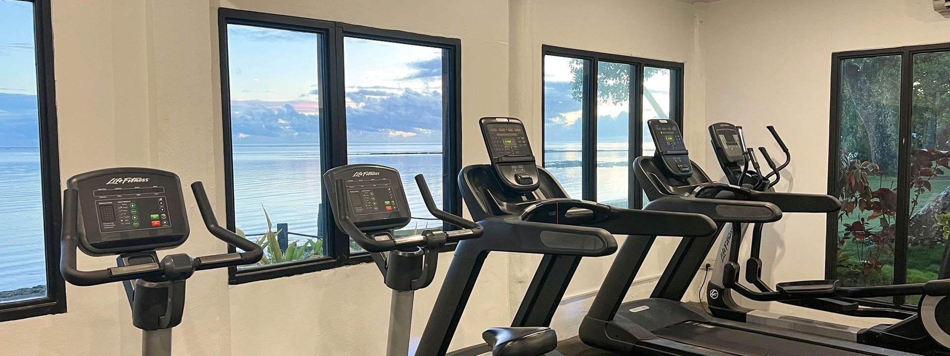 Treadmills and bikes by oceanview windows under bright ceiling lights at The Naviti Resort in Korolevu.
