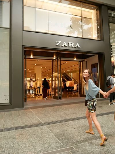 Couple holding hands walking to a Zara store at Queen Street Mall near Sofitel Brisbane Central