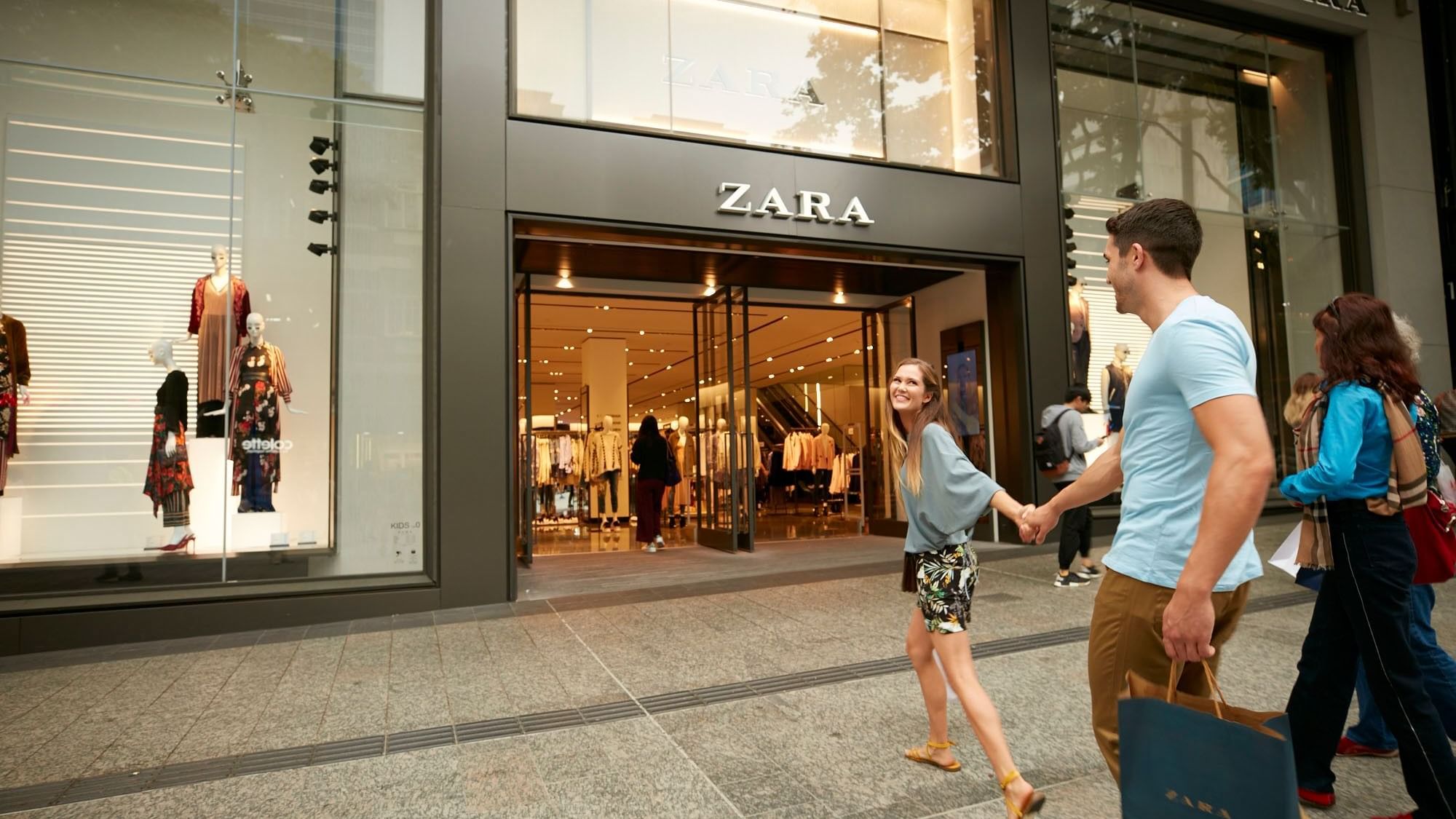 Couple holding hands walking to a Zara store at Queen Street Mall near Sofitel Brisbane Central