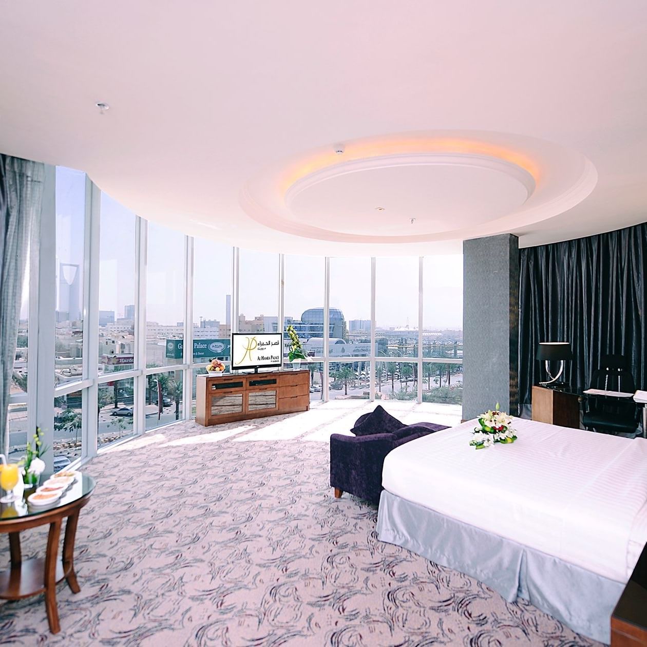 Télévision face au lit dans la suite panoramique avec vue sur la ville à l'Al Hamra Palace by Warwick Riyadh