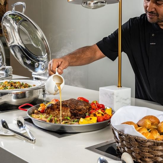 Executive Chef pouring gravy into meat dish in a restaurant at Pullman Sydney Hyde Park