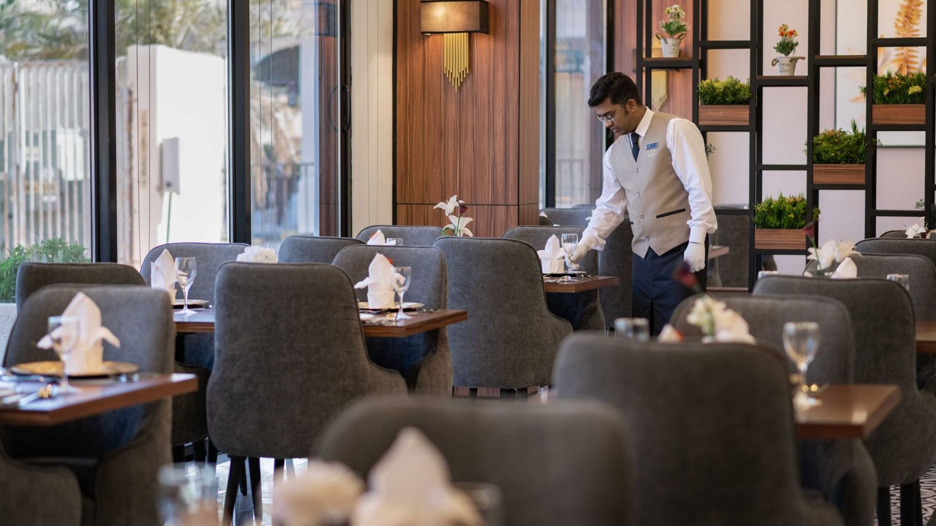 A waiter arranges tables in a restaurant at Warwick Hotels & Resorts