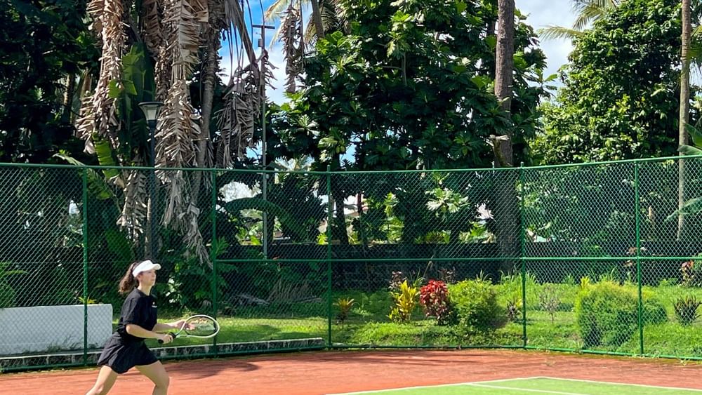 Woman playing tennis on the court at The Naviti Resort in Korolevu.