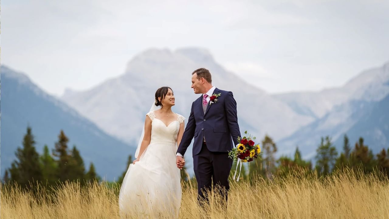 Two people who just got married in Canmore look at each other lovingly in front of the mountains.