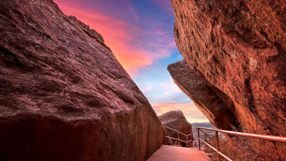Stone walkway with railings by red rock formations under a sunset sky at Warwick San Francisco