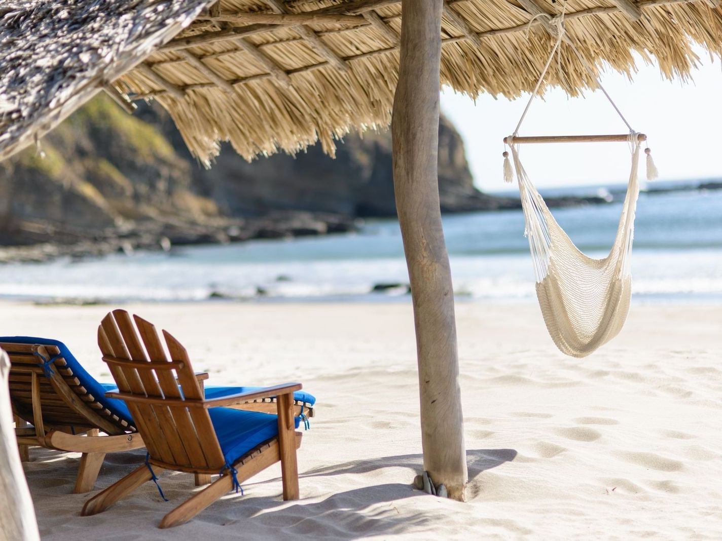 Hammock and chairs under a thatched roof by the sea at Morgan's Rock Reserve & Ecolodge, Ecolodge Nicaragua