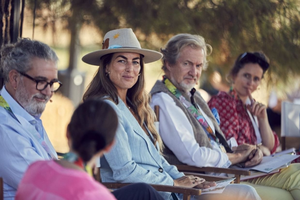 Woman in a wide-brimmed hat looking at the camera during an outdoor panel near Marbella Club
