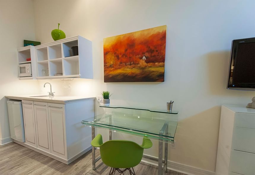 green chair at a glass desk near kitchenette with microwave and 