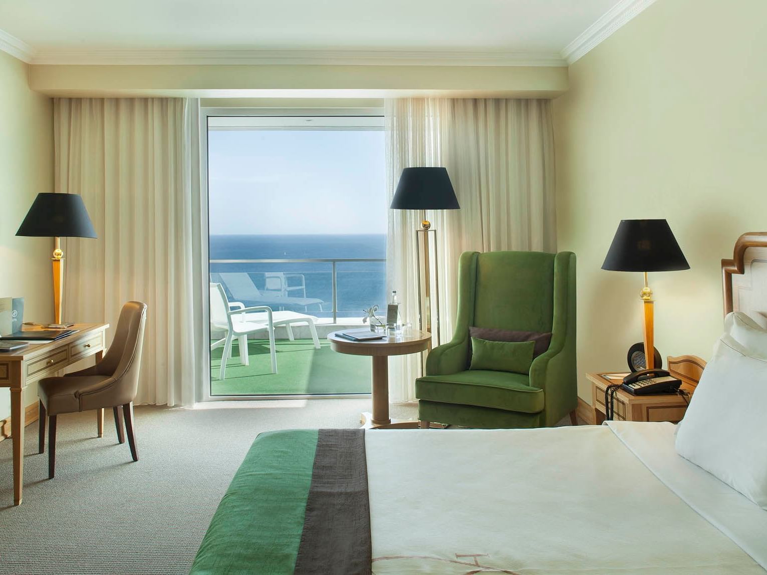 Deluxe Room with green armchair and balcony offering stunning ocean views at Hotel Cascais Miragem Health & Spa