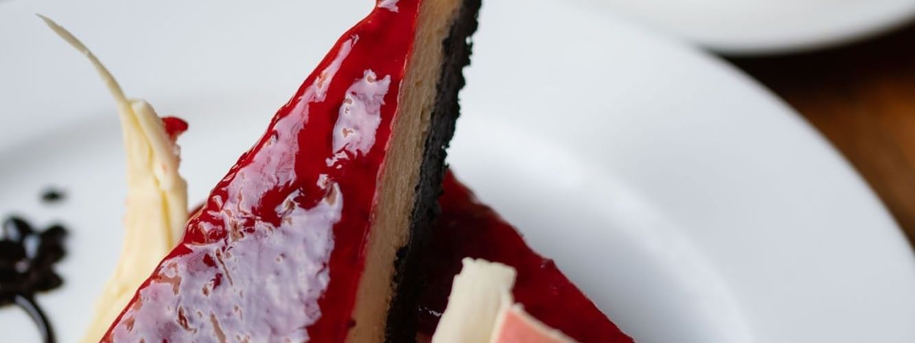 Two slices of cheesecake with a red glaze and dark crust served in the Artist Lobby Lounge at Warwick Hotel Jeddah