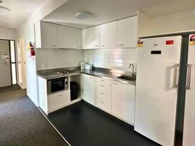 Modern kitchen area with white appliances and cabinets in student accommodation.