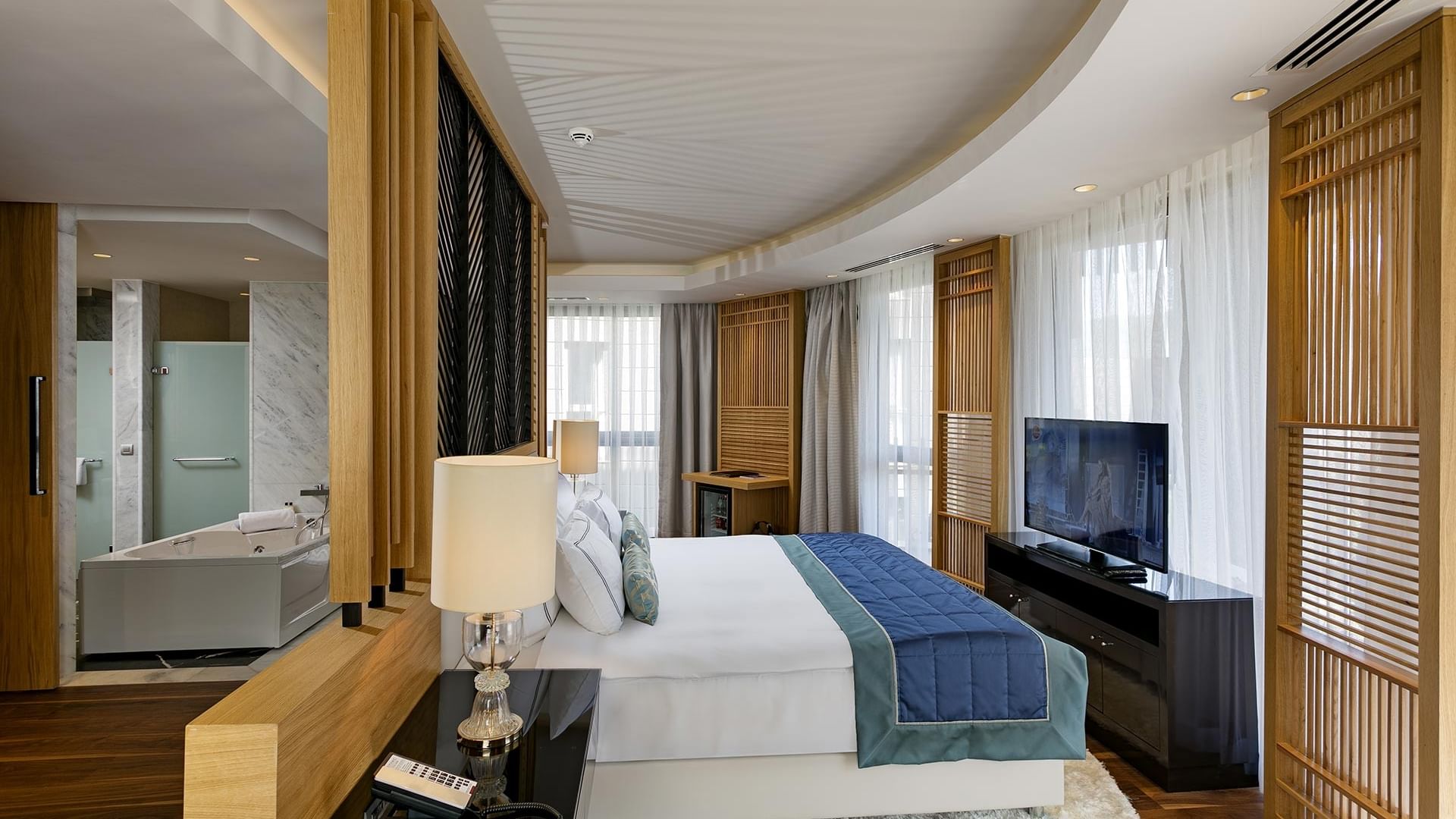 Presidential Villa's bedroom with a large bed, modern furniture, a TV, and a bathtub in the bathroom.