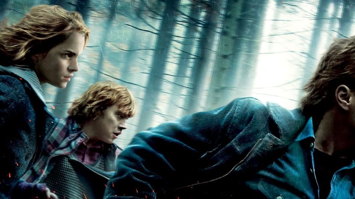Harry, Hermione, and Ron walking cautiously through a dark forest, with magical light glowing behind them