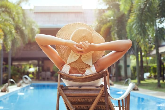 Woman in a hat enjoying a relaxing time by the pool near Hotel Grand Chancellor