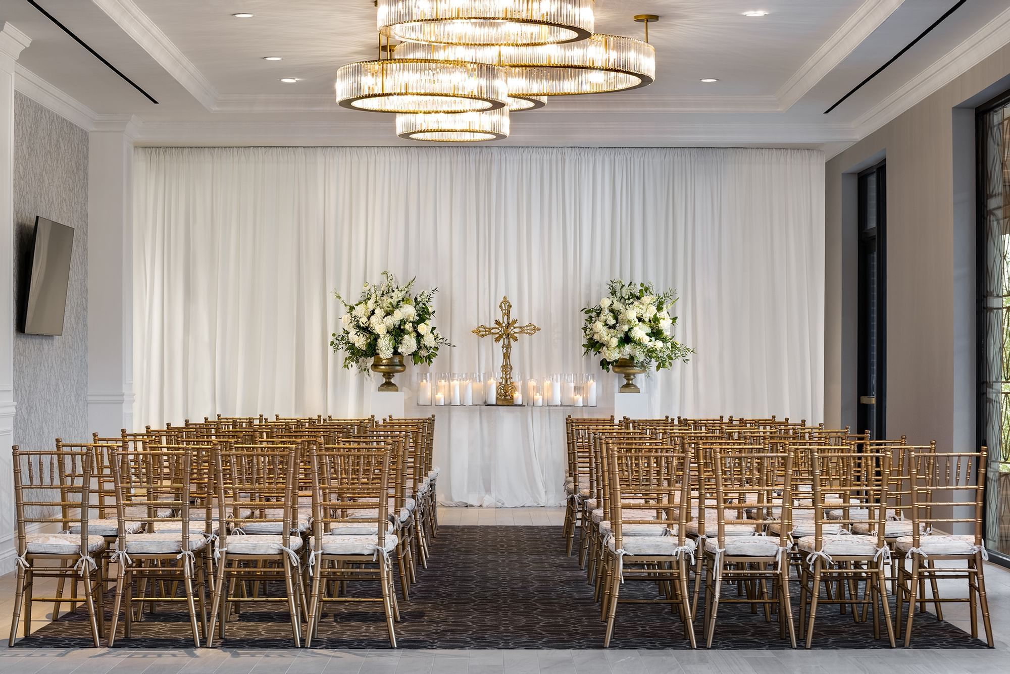 A luxurious event space with gold chairs, white floral arrangements, and candelabras.