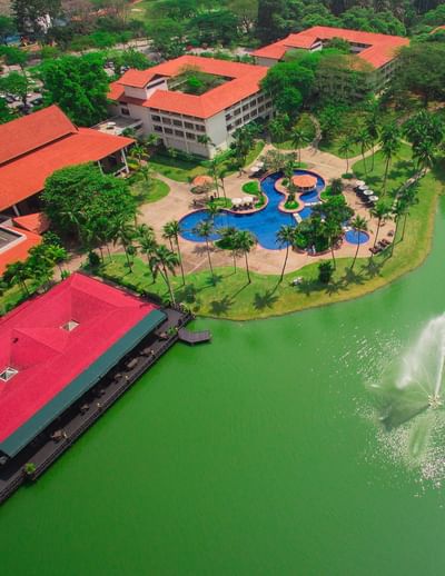 Aerial view of The Saujana Hotel Kuala Lumpur with pool, greenery, lake, and terracotta-roofed buildings