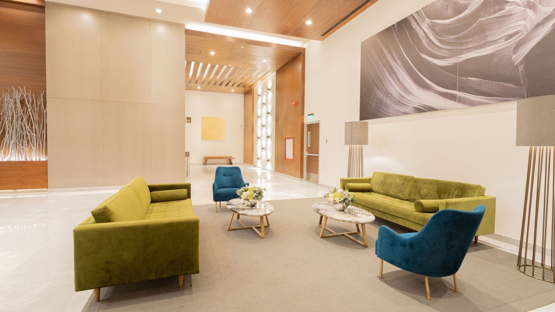 Modern hotel lobby with green velvet sofas, blue chairs, and marble coffee tables at Camino Real Fashion Drive, Monterrey